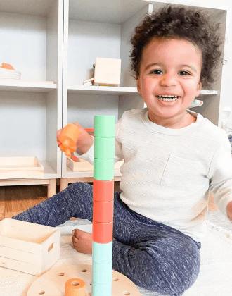 Child stacking on the Wooden Stacking Pegboard from The Adventurer Play Kit